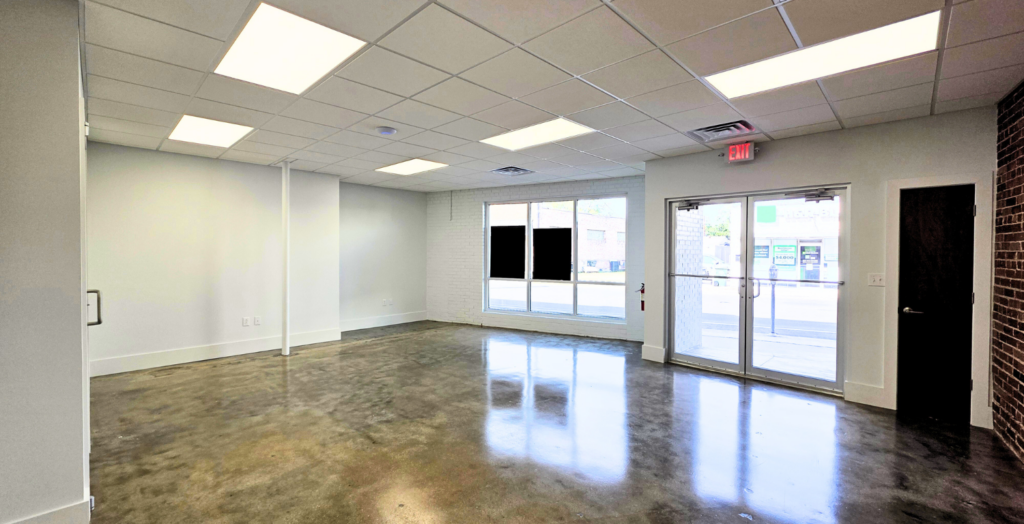 A group of three individuals gathered around a table, focused on a laptop in front of them.
