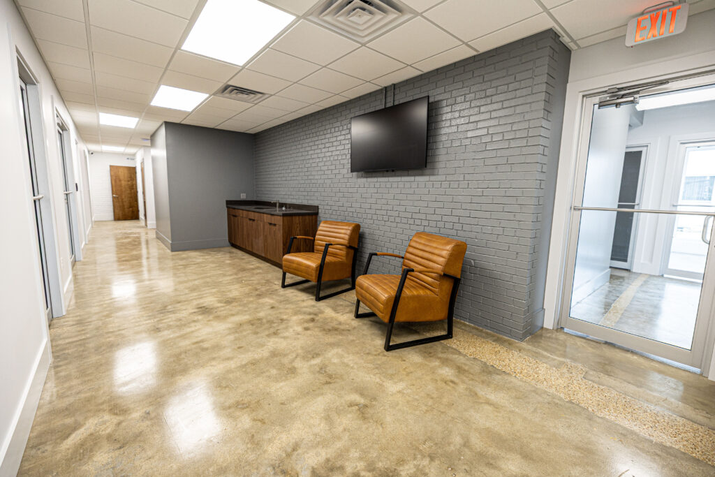 A group of three individuals gathered around a table, focused on a laptop in front of them.